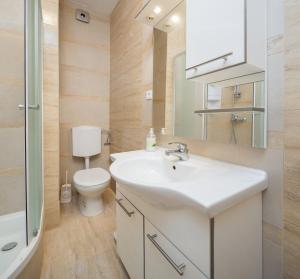 La salle de bains est pourvue d'un lavabo blanc et de toilettes. dans l'établissement ALBA Amazing Location Beach Apartments, à Biograd na Moru