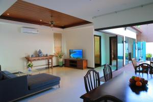 sala de estar con sofá y TV en Naiharn Beach Villa en Nai Harn Beach