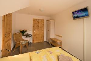 a bedroom with a bed and a desk and a tv on the wall at Pension "Zur Schönen Aussicht" in Mörlenbach