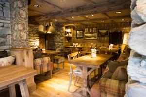 a restaurant with tables and chairs and a stone wall at The Queen's Head Hotel in Troutbeck