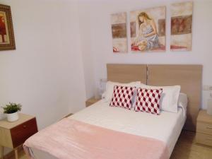 una camera con un letto con due cuscini rossi e bianchi di Apartamento Dos Aceras a Málaga