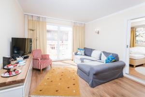 a living room with a couch and a tv at Hotel Sonnalm in Bad Kleinkirchheim