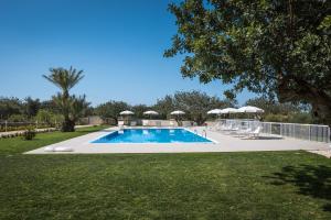 a swimming pool with chairs and umbrellas in a yard at Il Giardino dei Frangipani in Santa Croce Camerina