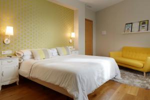 a bedroom with a large bed and a yellow chair at Hotel San Prudentzio in Getaria