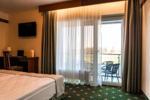 シュヴェントイにあるSPA Amber Palaceのベッド1台、窓、バルコニーが備わるホテルルームです。