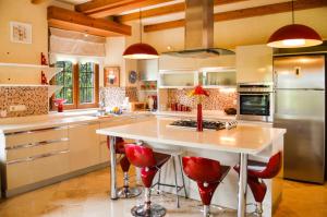Villa Mandarin by Important Group Travel في بيتيس: مطبخ مع جزيرة بيضاء كبيرة مع كراسي حمراء
