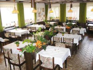 un restaurante con mesas blancas, sillas y plantas en Landhaus im Grund, en Lennestadt