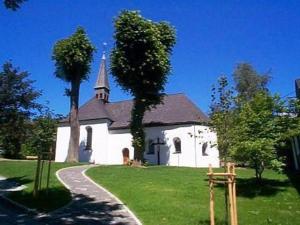 a small white church with a steeple on a green field at Landhaus im Grund in Lennestadt