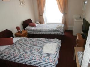 een hotelkamer met 2 bedden en een raam bij Monorene Guest House in Galashiels