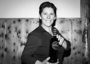 Una donna ha in mano una bottiglia di vino. di Eiger Guesthouse a Mürren
