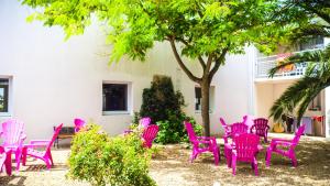 Village Vacances Passion Ré La Blanche في لو بوا بلاج-أون-ري: مجموعة من الكراسي وردية والطاولات تحت شجرة