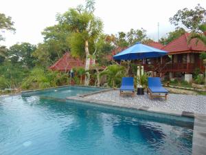 two chairs and an umbrella next to a swimming pool at Starfish Lembongan in Nusa Lembongan