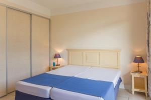 um quarto com uma grande cama branca com lençóis azuis em Résidence Héliotel Marine em Saint-Laurent-du-Var