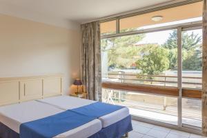 a bedroom with a bed and a large window at Résidence Héliotel Marine in Saint-Laurent-du-Var