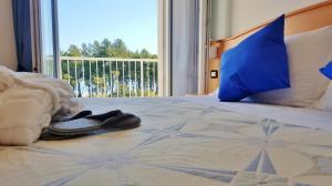 a bed with blue pillows and a pair of shoes on it at Hotel Mare Blu -- boutique in Pineto