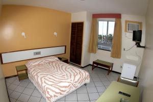アラカジュにあるNascimento Praia Hotelのベッドと窓が備わるホテルルーム