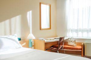 a bedroom with a bed and a desk and a chair at ibis Augsburg Hauptbahnhof in Augsburg