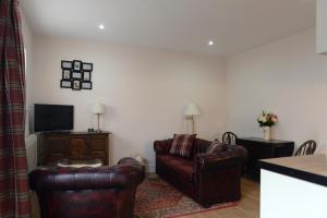 a living room with two chairs and a television at The Red Lion, Barn Accommodation in Thornby