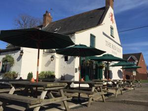 a group of picnic tables with umbrellas in front of a building at The Red Lion, Barn Accommodation in Thornby