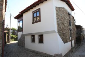 a white house with windows on a street at Casa do Ferrador in São Pedro de Vale do Conde