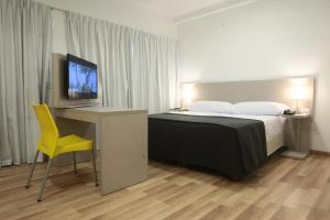 a bedroom with a bed and a desk with a television at Buen Pastor Capuchinos in Córdoba