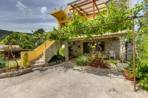 a house with a staircase and flowers in a yard at Apartman Astrid in Veli Lošinj