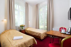 a hotel room with two beds and a table at Modlin Palace in Nowy Dwór Mazowiecki
