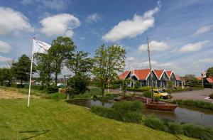 a boat in a river next to a house at EuroParcs De Rijp in De Rijp