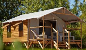 a log cabin with a porch and a tent at Camping Les Grillons in Embrun