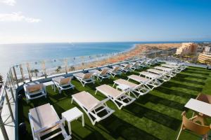 a row of lounge chairs and the beach at HL Suitehotel Playa del Inglés - Adults Only in Playa del Ingles