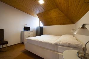 a bedroom with a white bed and a wooden ceiling at Penzion Na Náměstí in Mikulov