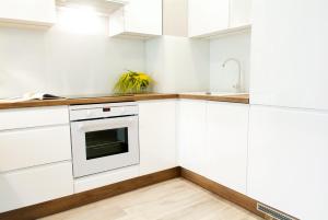 una cocina con armarios blancos y fregadero en Apartament 4 You, en Grudziądz