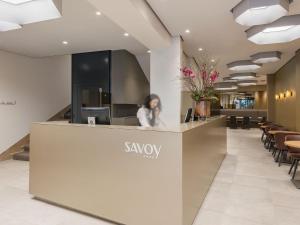 una mujer sentada en una recepción en un vestíbulo en Hotel Savoy en Berna