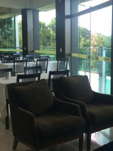 a restaurant with chairs and tables and windows at Hotel Floresta do Carajas in Parauapebas