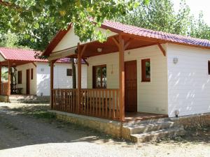 La Puebla de RodaにあるHoliday home Vakantiepark Isábena 6の木製ポーチ付きの小さな白いコテージ