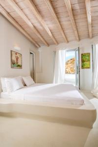 a white bedroom with a large bed and a window at Villa Aegean Lighthouse in Fanari
