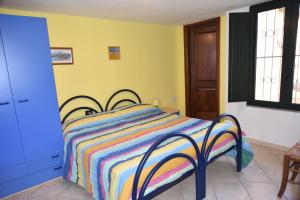 a bedroom with a bed with a colorful striped blanket at Holiday Home Marilu in Siniscola