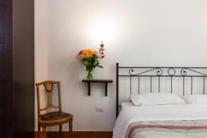ナポリにあるDon Pedro Rooms in the city centerのベッドルーム1室(ベッド1台、椅子、花瓶付)
