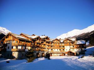 un grand bâtiment dans la neige avec des montagnes enneigées dans l'établissement Tidy apartment on the slopes in great Val Cenis, à Lanslebourg-Mont-Cenis