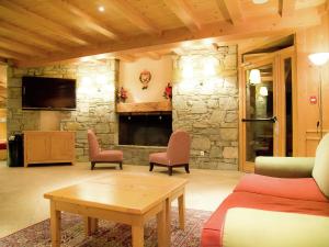 - un salon avec une cheminée en pierre, des chaises et une table dans l'établissement Tidy apartment on the slopes in great Val Cenis, à Lanslebourg-Mont-Cenis