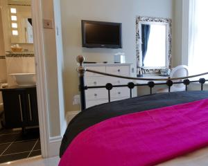 a bedroom with a bed and a tv and a mirror at The Grafton in Harrogate