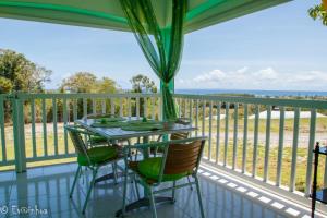 a table and chairs on a balcony with a view of the ocean at Les Gîtes Les Hauts de Montmain in Sainte-Anne