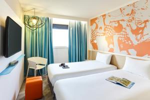 トゥールーズにあるibis Styles Toulouse Nord Sesquieresのベッド2台とテレビが備わるホテルルームです。