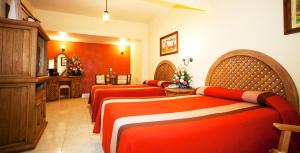 3 camas en una habitación de hotel con sábanas rojas en Gran Hotel Pátzcuaro, en Pátzcuaro
