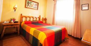 1 dormitorio con 1 cama colorida, mesa y ventana en Gran Hotel Pátzcuaro, en Pátzcuaro