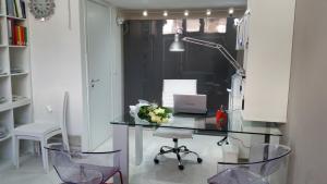 Habitación con escritorio de cristal con ordenador portátil y sillas. en I Delfini, en Agropoli