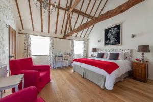 a bedroom with a large bed and a red chair at Hubbard's Luxury Bed and Breakfast in South Creake