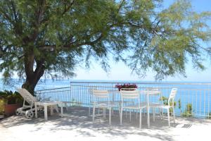 a table and chairs under a tree next to the ocean at Blu OltreMare in Acciaroli