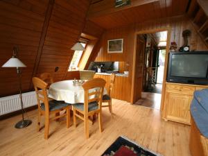 ein Esszimmer mit einem Tisch mit Stühlen und einem TV in der Unterkunft Wooden chalet with oven, in Oberharz near a lake in Clausthal-Zellerfeld