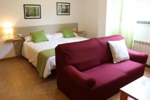 a bedroom with a bed and a purple couch at Apartamentos Turísticos Cancelas by Bossh Hotels in Santiago de Compostela